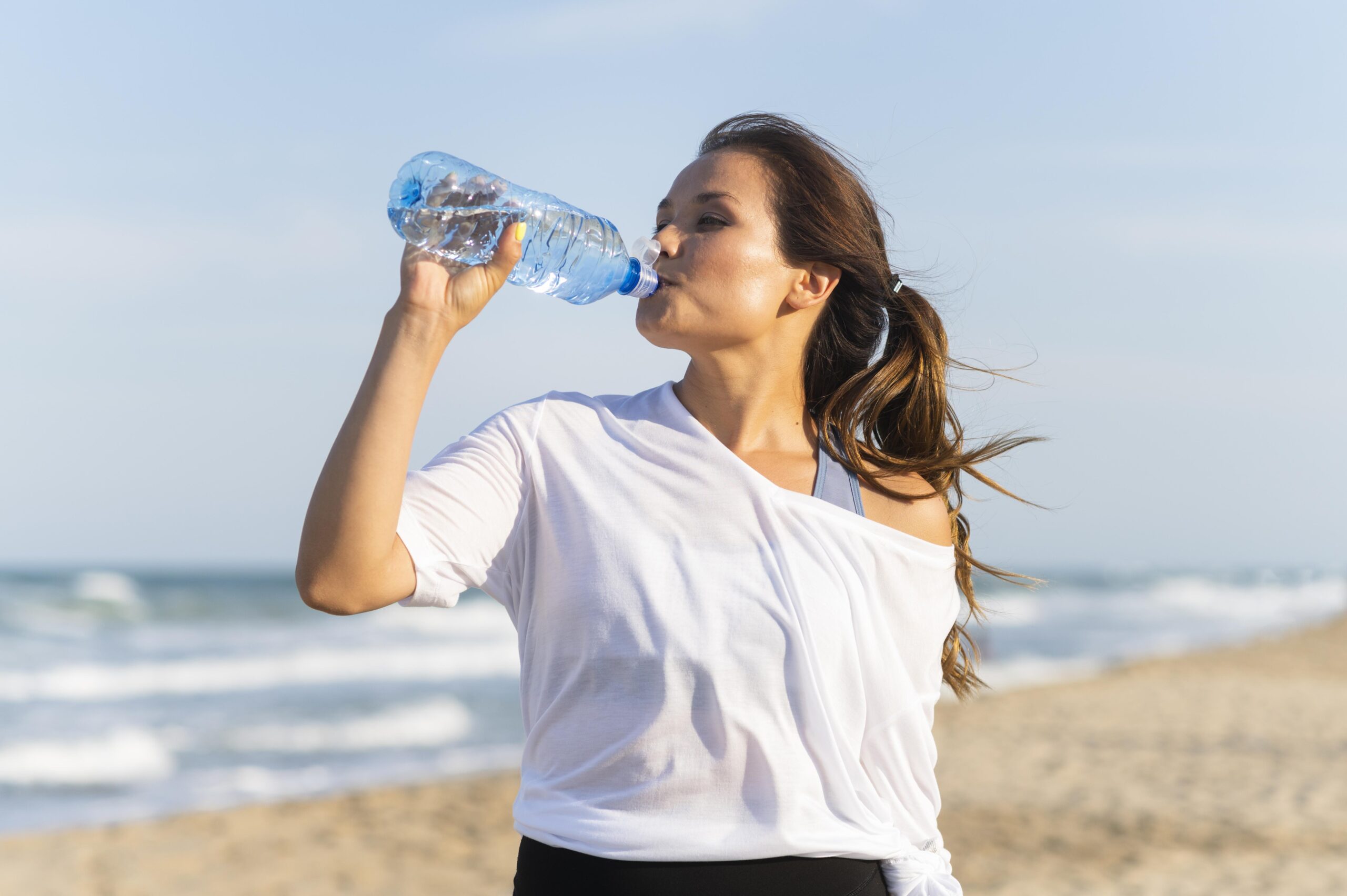 Пить настоящее время. Пить воду на пляже. Девушка пьет из кувшина воду. Девушка пьет воду на пляже. Идеи фото с бутылкой воды.